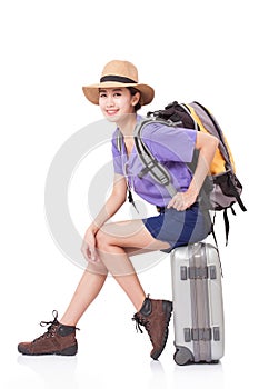 Woman traveler sitting on suitcase with backpack