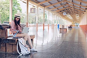Woman traveler using computer at train station. Travel journey trip concept