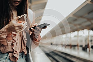 Woman traveler using mobile smart phone at train station. Travel journey trip concept
