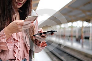 Woman traveler using mobile smart phone at train station. Travel journey trip concept