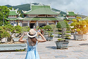 Woman traveler visiting at Linh Ung Pagoda temple or Lady big Buddha. Tourist with blue dress and hat traveling in Da Nang city.