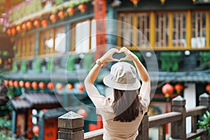 woman traveler visiting in Taiwan, Tourist with hat sightseeing in Jiufen Old Street village with Tea House background. landmark