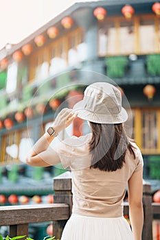 woman traveler visiting in Taiwan, Tourist with hat sightseeing in Jiufen Old Street village with Tea House background. landmark