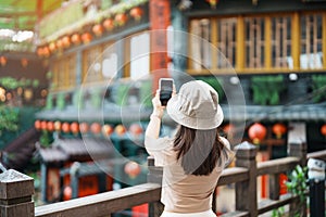 woman traveler visiting in Taiwan, Tourist taking photo and sightseeing in Jiufen Old Street village with Tea House background.