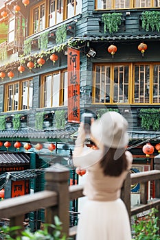 woman traveler visiting in Taiwan, Tourist taking photo and sightseeing in Jiufen Old Street village with Tea House background.