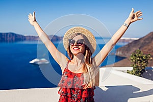 Woman traveler walking raising hands in Thera, Santorini island, Greece. Tourism, traveling, summer vacation