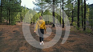 Woman traveler walks around a pine forest on top of the Chinyero volcano in the national park of the Teide volcano on