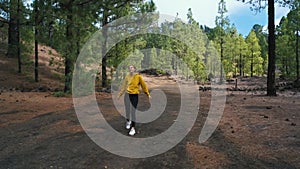 Woman traveler walks around a pine forest on top of the Chinyero volcano in the national park of the Teide volcano on