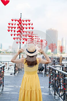 Woman Traveler with yellow dress visiting in Da Nang. Tourist sightseeing at love lock bridge. Landmark and popular. Vietnam and