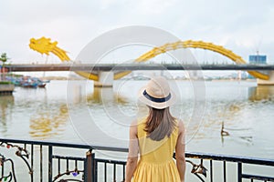 Woman Traveler with yellow dress visiting in Da Nang. Tourist sightseeing the river view with Dragon bridge at love lock bridge.