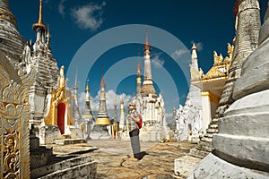 Woman traveling with backpack and looks at stupas Buddhist temple