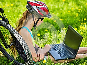 Woman traveling bicycle in summer park. Girl watch laptop.