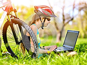 Woman traveling bicycle in summer park. Girl watch laptop.