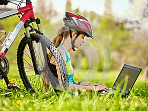 Woman traveling bicycle in summer park. Girl watch laptop.
