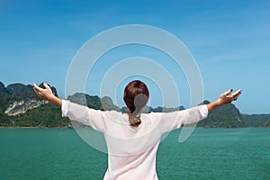 Woman traveling by boat among the islands with arms up feeling free bliss back view