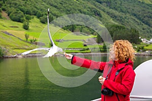 Woman traveling on ferry boat and feeding seagull