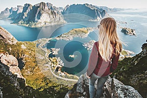 Woman traveling in Norway standing on cliff of Reinebringen mountain aerial view