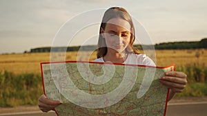 A woman is traveling, resting on vacation. A woman looks at a map on a rural road in the middle of a field
