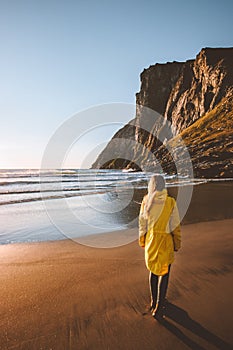 Woman traveling solo walking on beach looking at sunset ocean view