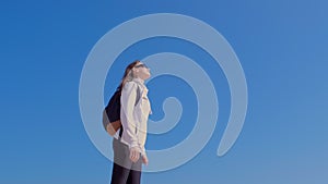 Woman traveller with backpack enjoys nature on blue sky background on vacation.