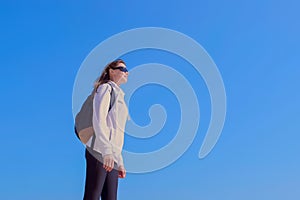 Woman traveller with backpack enjoys nature on blue sky background on vacation.
