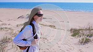 Woman traveller with backpack is looking around in sea sand beach on vacation.