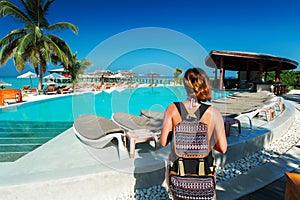 Woman traveller with backpack near swimming pool at tropical island