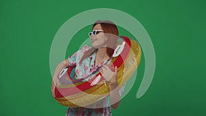 Woman traveller in dress with inflatable tube ring over shoulder, smiling happy face expression. Isolated on green