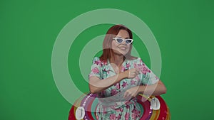 Woman traveller in glasses dancing funnily with inflatable tube ring on, smiling and happy face looking at the camera