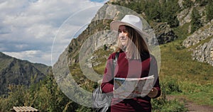 Woman traveller with map hiking in mountains valley on a route in national park.