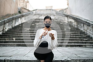 Woman traveller outdoors alone on the empty street using hand sanitizer spray, spraying disinfectant on bare hands.Cautious person