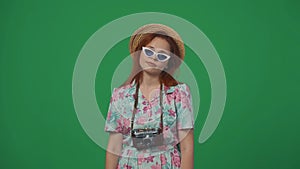 Woman traveller in straw hat with old film camera looking tired from excursions on vacation. Isolated on green