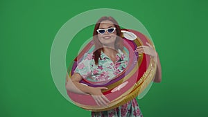 Woman traveller walks into frame with inflatable tube ring over shoulder, smiling and showing thumbs up, looking at the