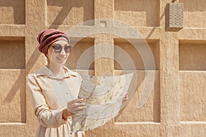 Woman travels alone and looks at a map against the wall of an ancient city in the Middle East region or somewhere in Morocco