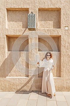 Woman travels alone and looks at a map against the wall of an ancient city in the Middle East region or somewhere in Morocco