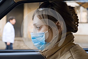 Woman travels on automobile in a protective mask