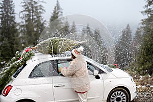 Woman travels by car with presents and Christmas tree on the mountain road