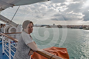 Woman travels on ferry ship. Livorno in the background, Italy