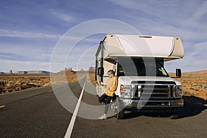 A woman travels by motorhome through Monument Valley in the USA desert and checks her mobile phone parked