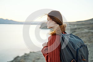 woman travels in the mountains in nature near the sea with a backpack on her back