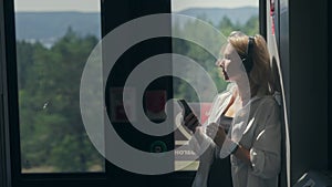 A woman travels to and from work every day by train. Blonde woman in headphones listens to music from the phone