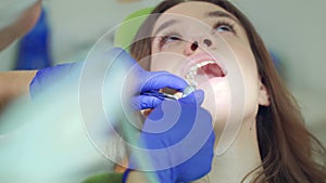 Woman treating teeth at family dentist. Dentist hands working at woman mouth