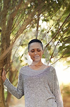 Woman, tree and eyes closed for peace in woods, travel and thinking about life, mindfulness and sunshine. Forest, nature