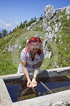 Woman trekker refreshing high in the mountains