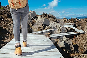 Woman trekker walking on wooden board path