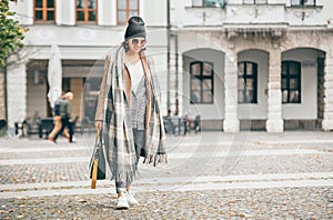 Woman in trend multilayered outfit walks in autumn city street.