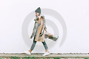 Woman in trend multilayered outfit walks in autumn city street.