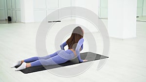 Woman in trendy colour sportswear doing stretch in gym