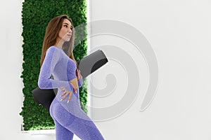 Woman in trendy colour sportswear holding sports mat