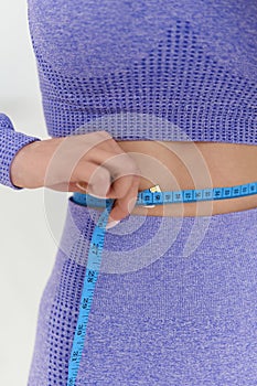 Woman in trendy colour sportswear holding tape measure